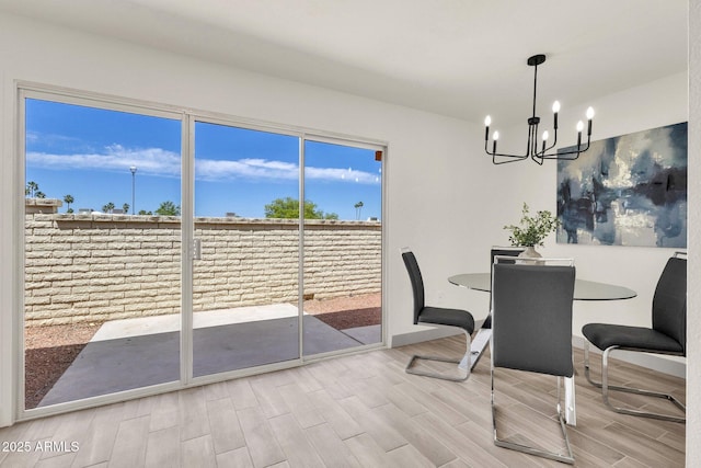 dining space featuring wood finished floors, a notable chandelier, and baseboards