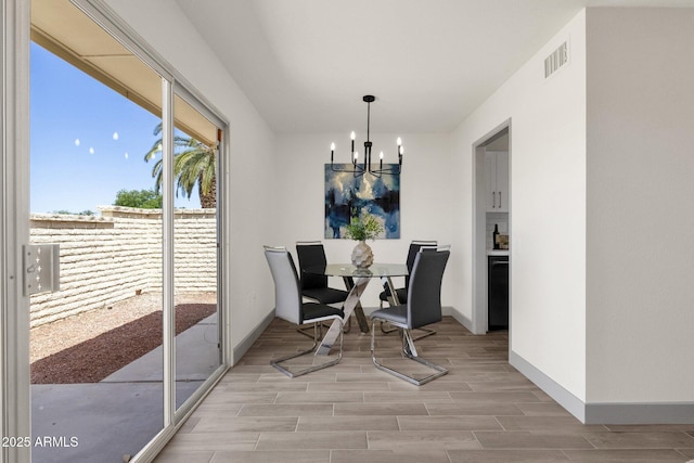 dining room featuring a chandelier, visible vents, wood tiled floor, and baseboards