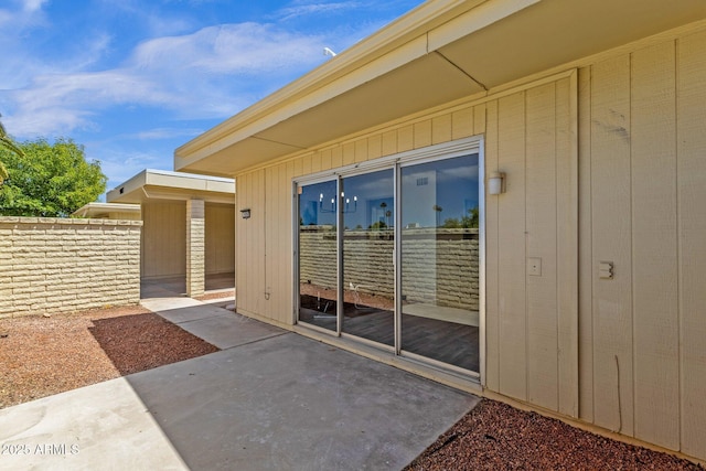 property entrance with fence and a patio area