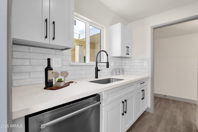 kitchen with a sink, backsplash, light countertops, dishwasher, and white cabinets