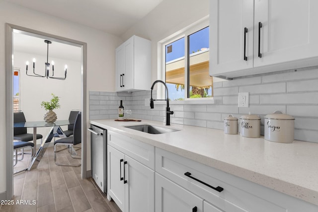 kitchen featuring light wood finished floors, a sink, a chandelier, backsplash, and white cabinets