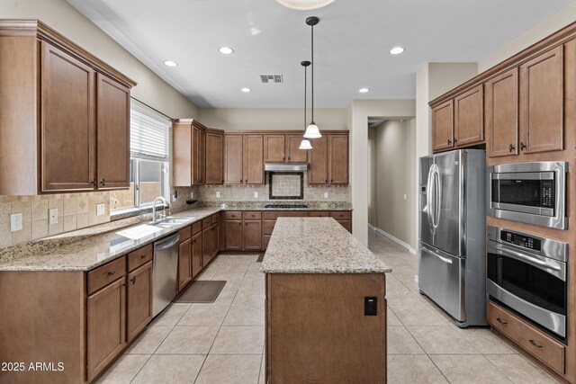 211 W New Dawn Dr, Chandler, AZ 85248 - kitchen featuring appliances with stainless steel finishes, a kitchen island, decorative backsplash, a sink, and light stone countertops