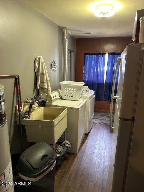 laundry area featuring hardwood / wood-style floors, washer and clothes dryer, sink, and water heater