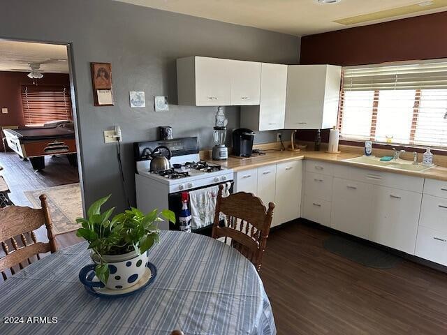 kitchen featuring dark hardwood / wood-style flooring, sink, white gas range oven, and white cabinets