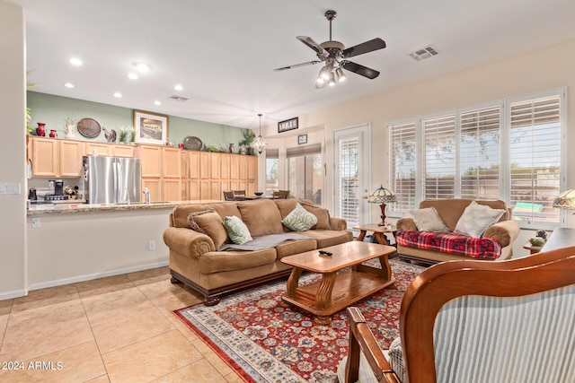 tiled living room featuring plenty of natural light and ceiling fan with notable chandelier