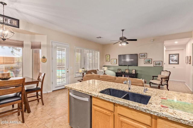 kitchen featuring stainless steel dishwasher, decorative light fixtures, light stone countertops, and sink