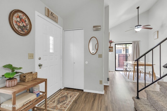 foyer with baseboards, a ceiling fan, dark wood-style floors, stairway, and high vaulted ceiling