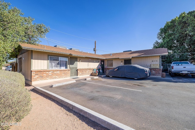 ranch-style house with brick siding, uncovered parking, and fence