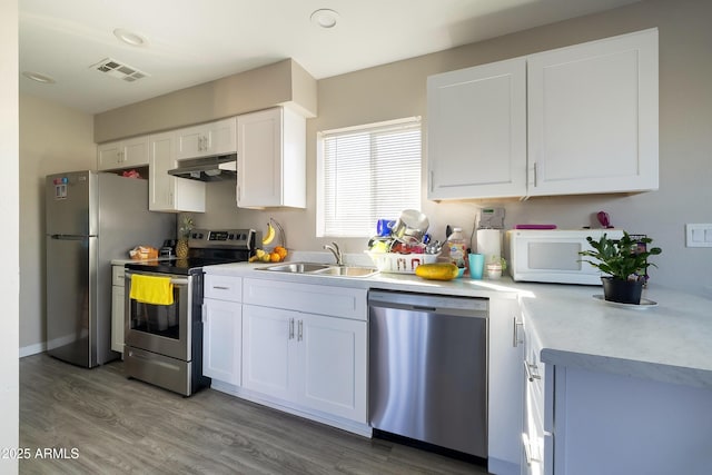 kitchen with white cabinetry, visible vents, under cabinet range hood, a sink, and stainless steel appliances
