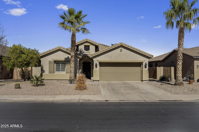 mediterranean / spanish house featuring a garage, concrete driveway, a tiled roof, and stucco siding