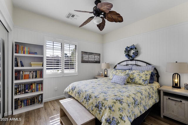 bedroom with wood finished floors, visible vents, and a ceiling fan