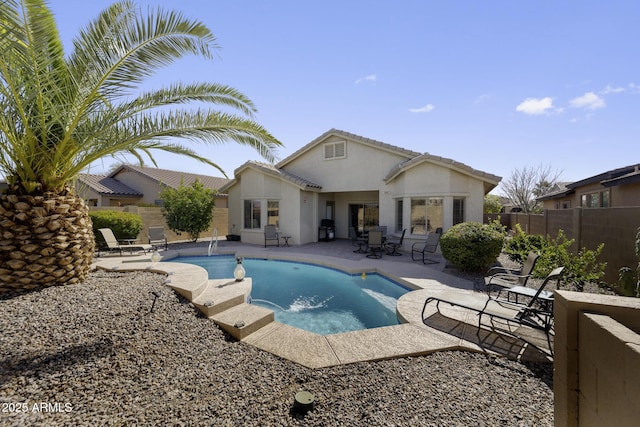 rear view of house featuring a fenced in pool, stucco siding, fence, and a patio