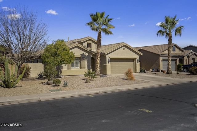 mediterranean / spanish home featuring concrete driveway, a tile roof, an attached garage, and stucco siding