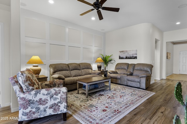 living area featuring baseboards, ceiling fan, wood finished floors, a decorative wall, and recessed lighting