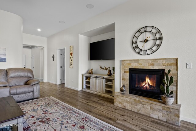 living area featuring a tiled fireplace, baseboards, dark wood-style flooring, and recessed lighting