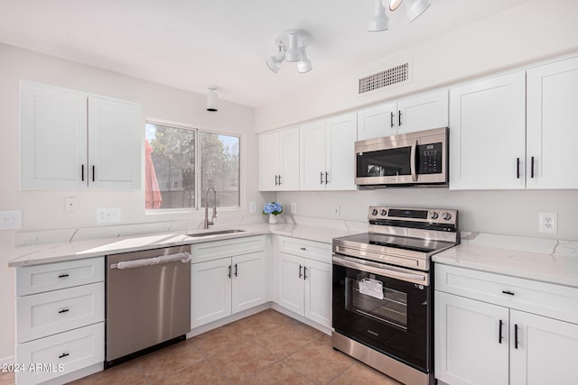 kitchen featuring light tile patterned floors, white cabinetry, light stone countertops, sink, and stainless steel appliances