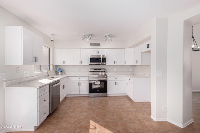 kitchen with white cabinetry, light stone countertops, light tile patterned flooring, sink, and stainless steel appliances