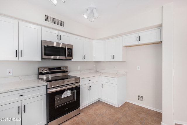 kitchen featuring light tile patterned flooring, white cabinets, stainless steel appliances, and light stone counters