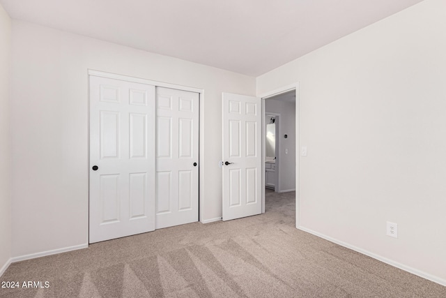 unfurnished bedroom featuring a closet and light carpet