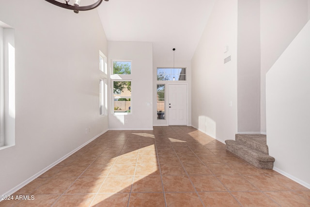 foyer entrance featuring tile patterned floors, a chandelier, and high vaulted ceiling