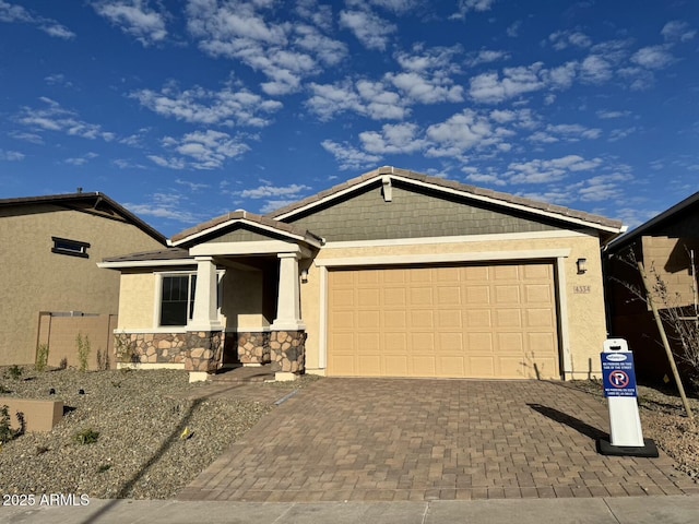 view of front facade featuring stone siding, stucco siding, an attached garage, and decorative driveway
