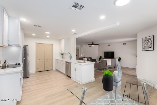 kitchen with kitchen peninsula, appliances with stainless steel finishes, light wood-type flooring, sink, and white cabinetry