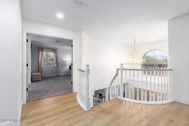 stairway featuring hardwood / wood-style flooring and a notable chandelier