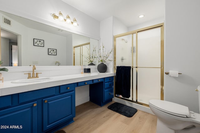 bathroom with vanity, toilet, wood-type flooring, and a shower with door