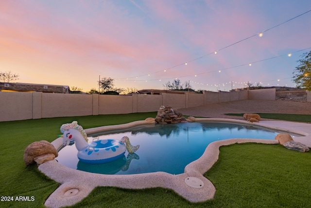 pool at dusk featuring a yard