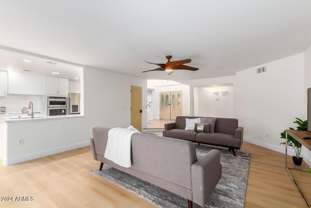 living room featuring ceiling fan and light hardwood / wood-style flooring