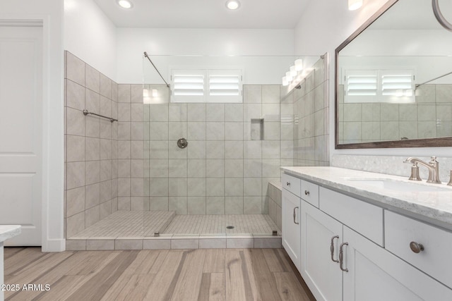 bathroom featuring tiled shower, vanity, and wood-type flooring