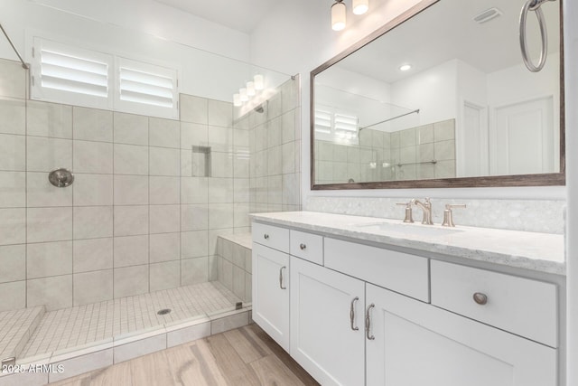 bathroom with hardwood / wood-style flooring, vanity, and tiled shower