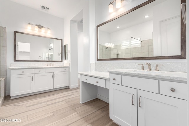 bathroom featuring vanity, wood-type flooring, and a tile shower