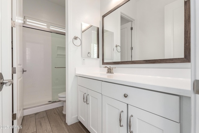 bathroom with an enclosed shower, vanity, hardwood / wood-style flooring, and toilet