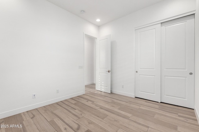 unfurnished bedroom with light hardwood / wood-style floors and a closet