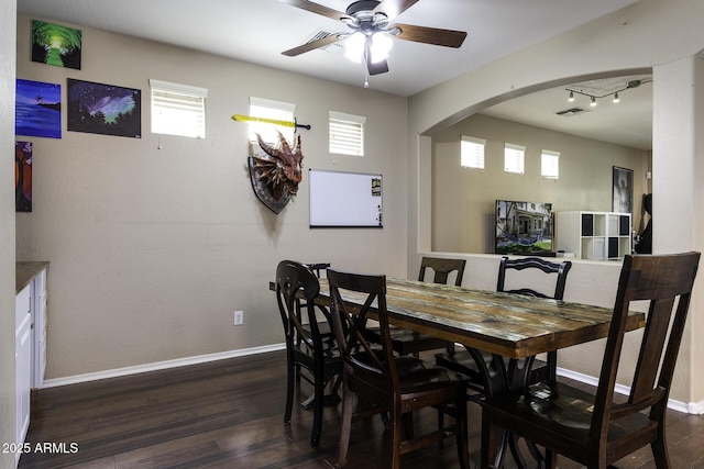 dining room featuring visible vents, baseboards, ceiling fan, arched walkways, and dark wood finished floors