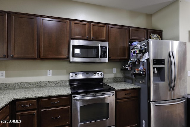 kitchen with light stone counters, stainless steel appliances, and dark brown cabinets