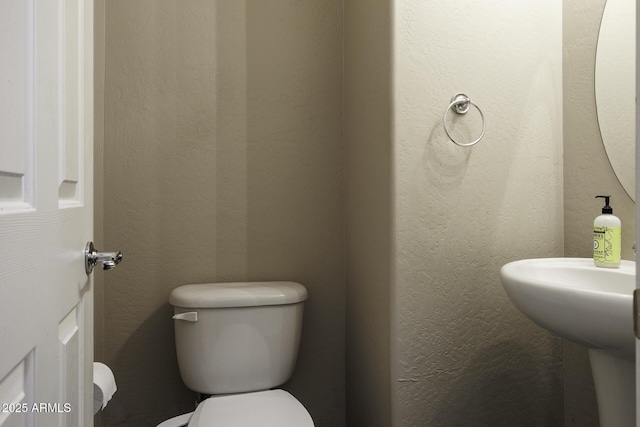 bathroom featuring a textured wall and toilet