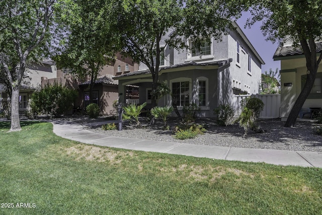 view of property hidden behind natural elements with a front yard and stucco siding