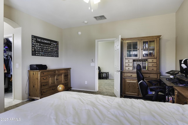 bedroom featuring visible vents, carpet floors, baseboards, a walk in closet, and arched walkways