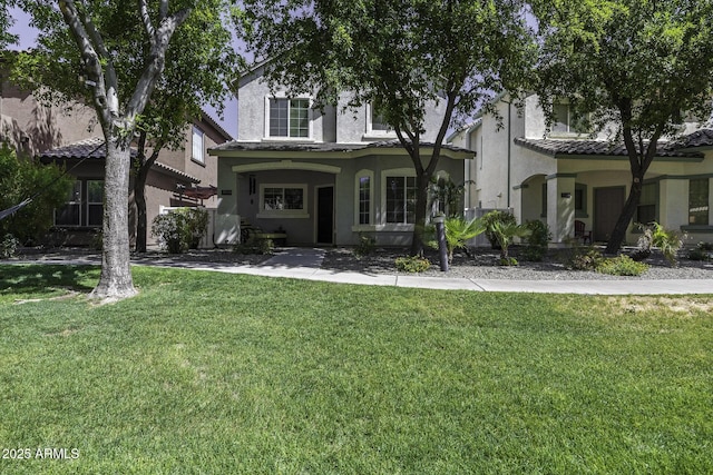 view of front of home featuring stucco siding, a tiled roof, and a front yard