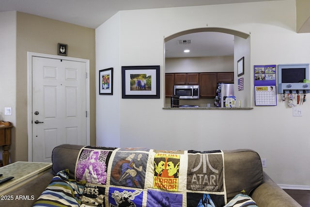living room featuring arched walkways, baseboards, recessed lighting, and visible vents