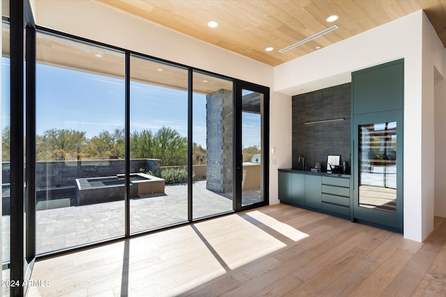 doorway with light hardwood / wood-style floors, wood ceiling, and sink