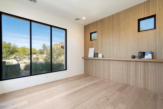 interior space featuring wood walls, plenty of natural light, and light hardwood / wood-style floors