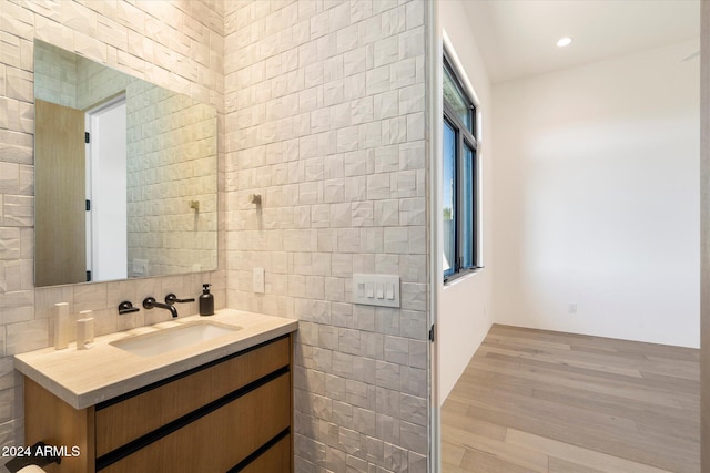 bathroom featuring recessed lighting, wood finished floors, vanity, tile walls, and tasteful backsplash