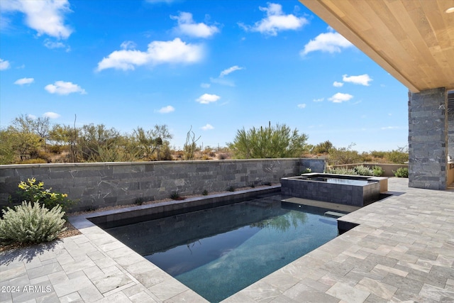 outdoor pool featuring a patio area and an in ground hot tub