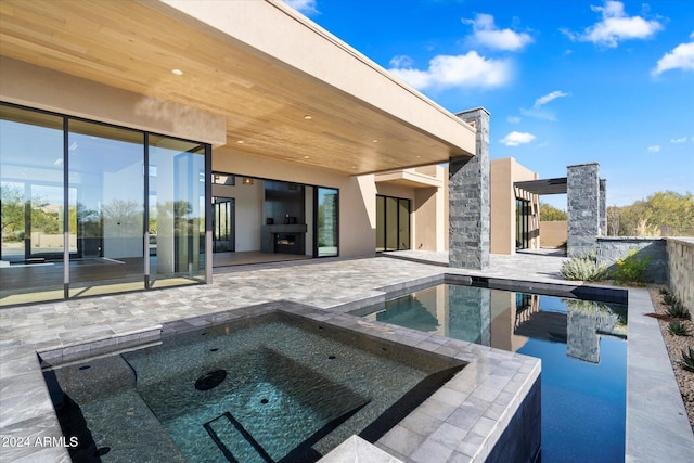 view of pool with a patio area, an in ground hot tub, and an outdoor stone fireplace