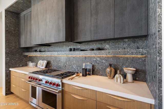 kitchen with light countertops, double oven range, decorative backsplash, and modern cabinets