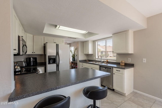 2455 E Broadway Rd Unit 115, Mesa, AZ 85204 - kitchen with appliances with stainless steel finishes, a sink, a peninsula, dark countertops, and a kitchen bar