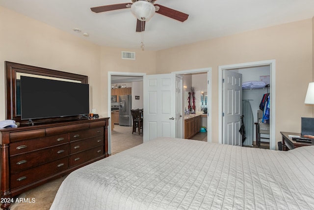 bedroom with ensuite bath, stainless steel fridge, light carpet, and a spacious closet